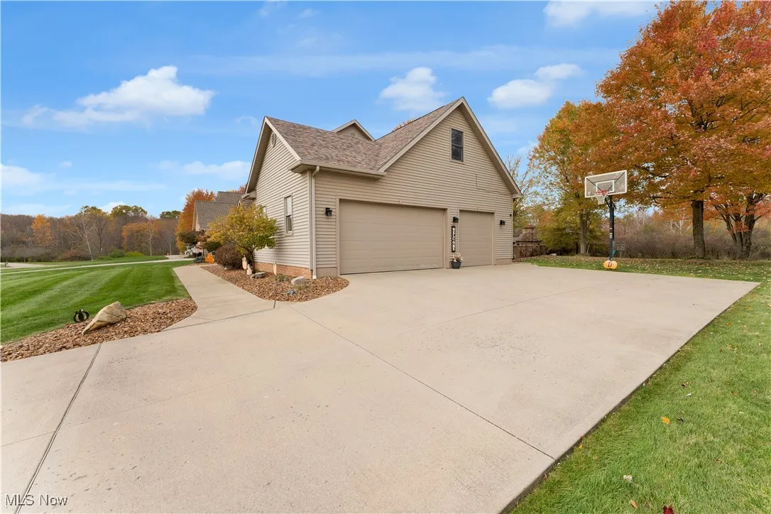 View of side of home featuring a lawn and concrete driveway