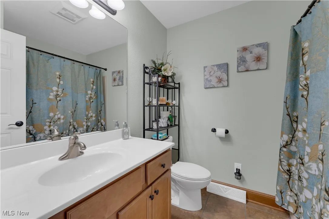 Bathroom with vanity, dark tile patterned floors, and a shower with shower curtain