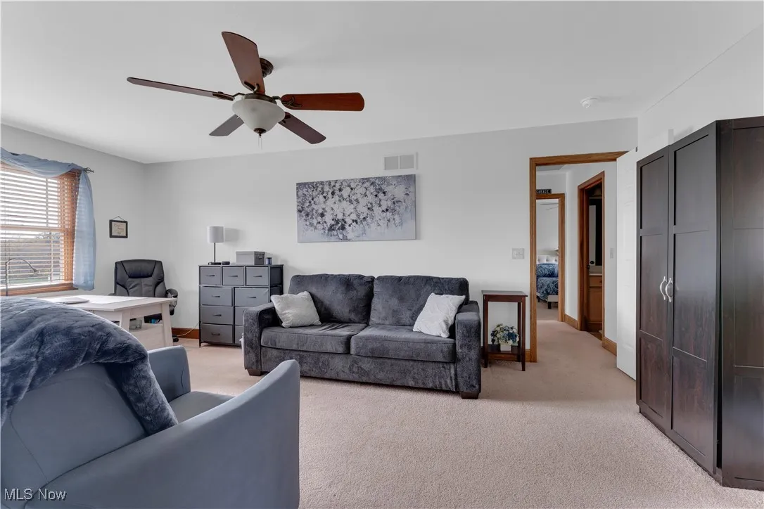 Living area with light colored carpet and a ceiling fan