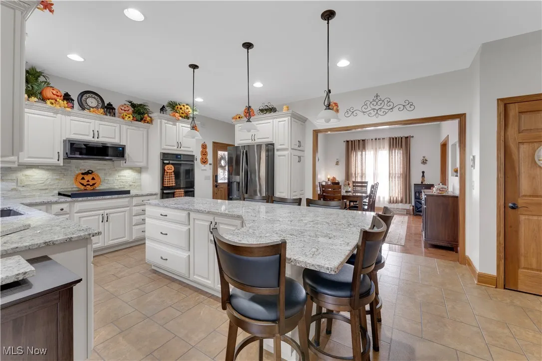 Kitchen with light stone counters, white cabinets, a breakfast bar, and recessed lighting