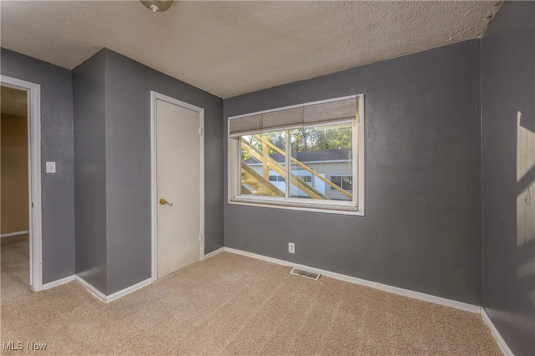 Unfurnished bedroom featuring light carpet and a textured ceiling
