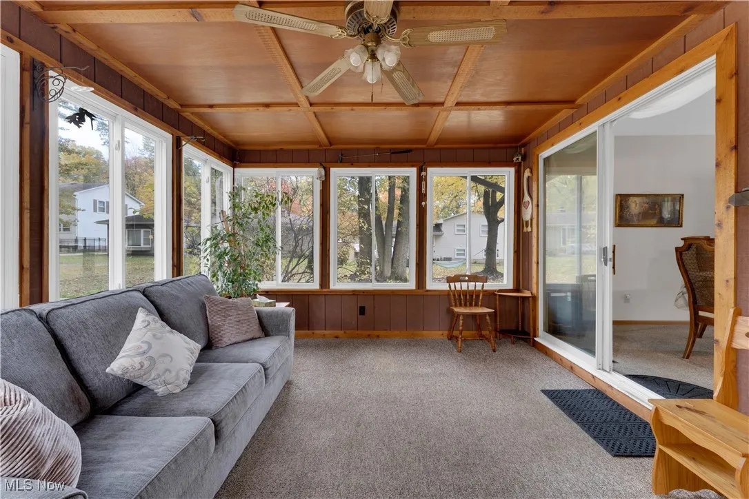 Sunroom with ceiling fan, outdoor lounge area, and beamed ceiling