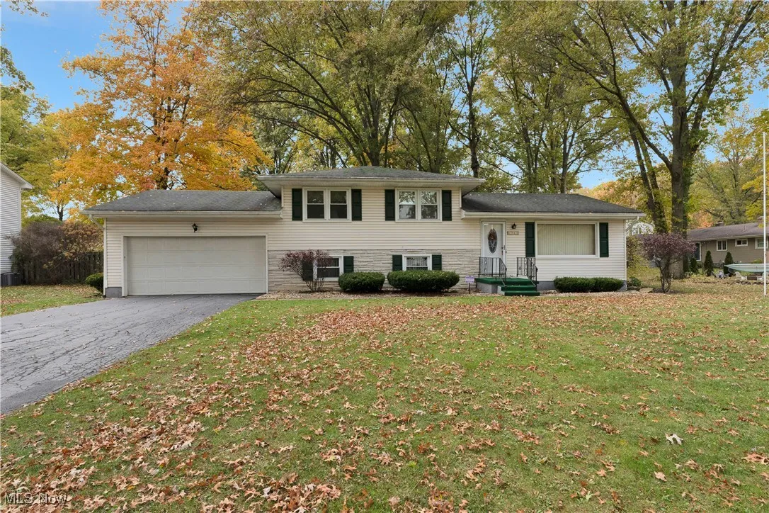 Split level home with a garage, asphalt driveway, and a front lawn
