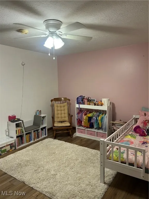 Bedroom featuring a textured ceiling, dark wood-type flooring, and a ceiling fan