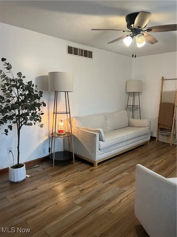 Living area featuring wood finished floors, ceiling fan, and a textured ceiling