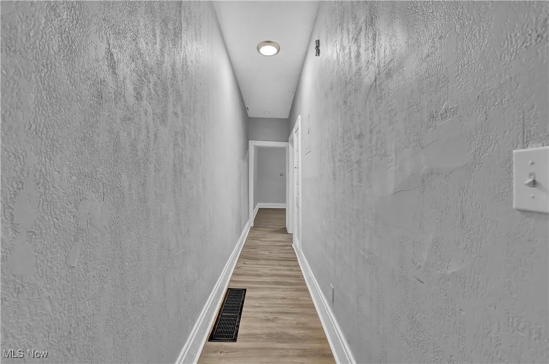 Corridor with a textured wall and light wood-style floors