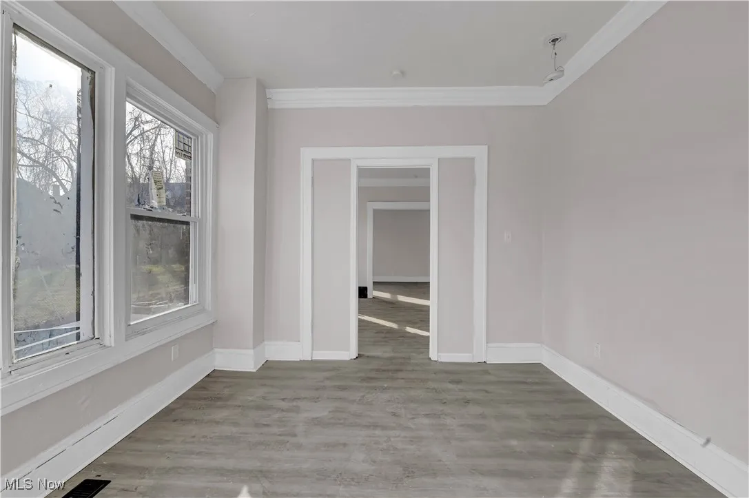 Empty room with ornamental molding and light wood-type flooring