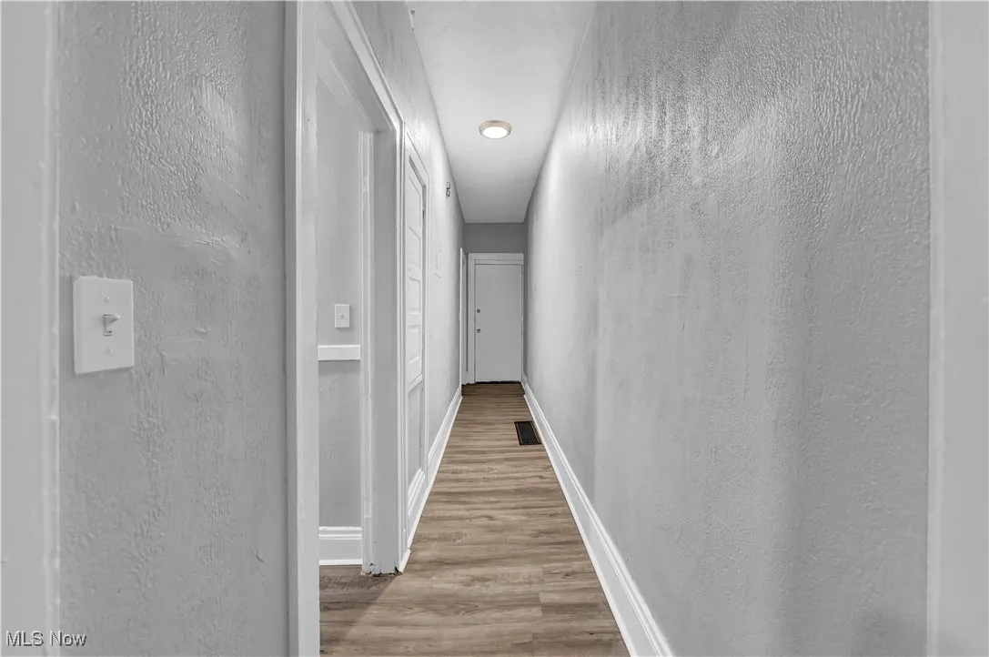 Corridor with a textured wall and light wood-type flooring