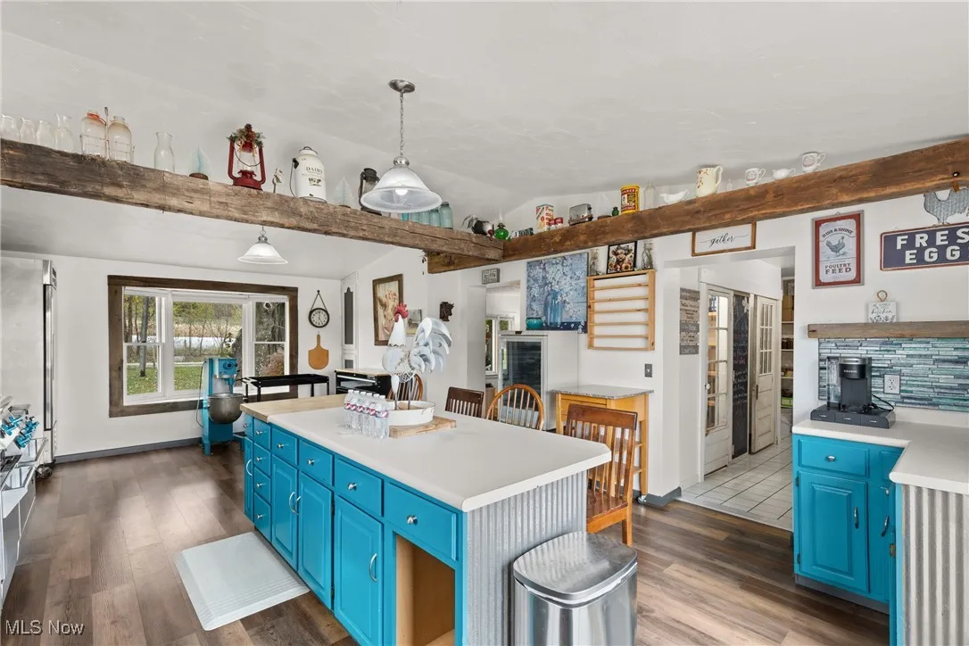 Kitchen with blue cabinets, light countertops, hanging light fixtures, dark wood-style floors, and lofted ceiling