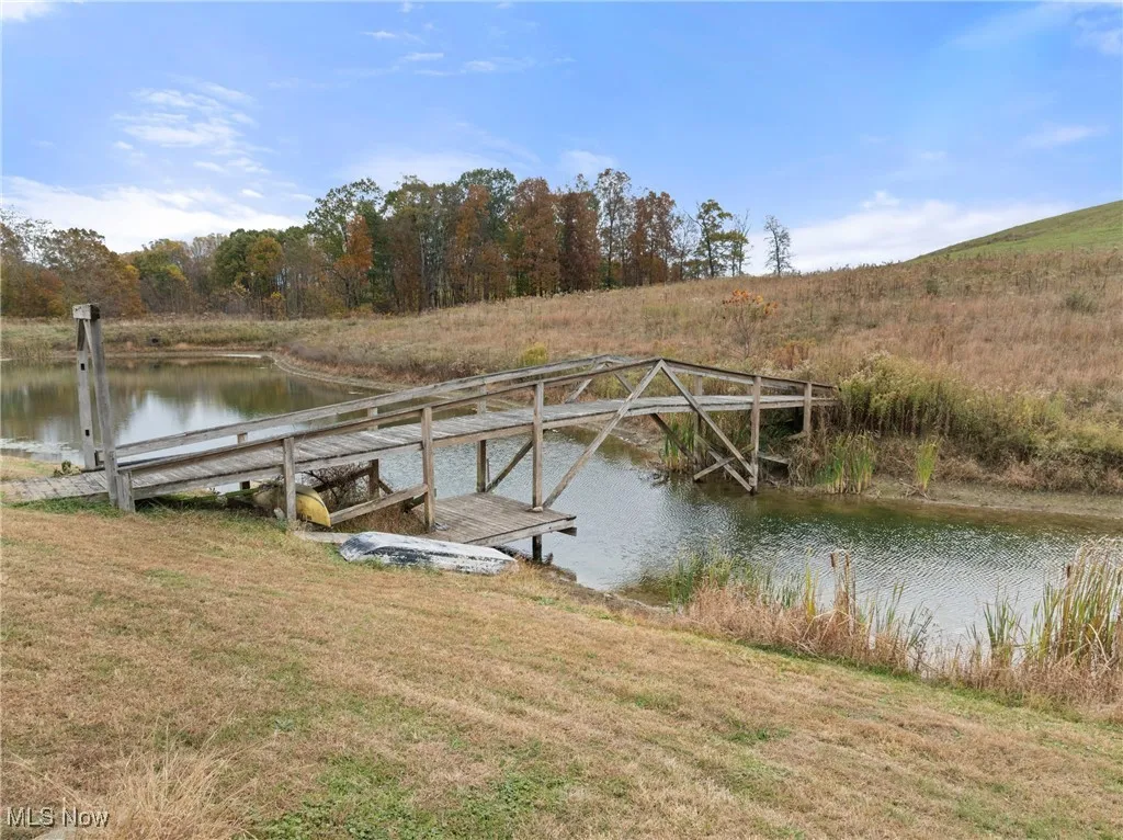 Dock area with a water view and a lawn