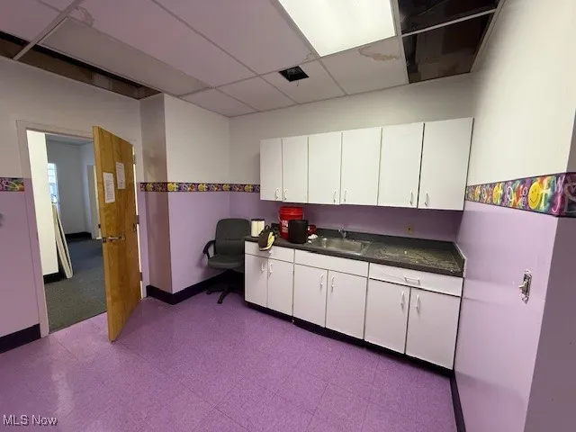 Kitchen with dark countertops, white cabinets, and a drop ceiling