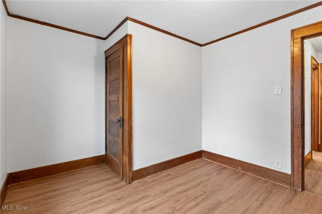 Unfurnished room with crown molding and wood finished floors