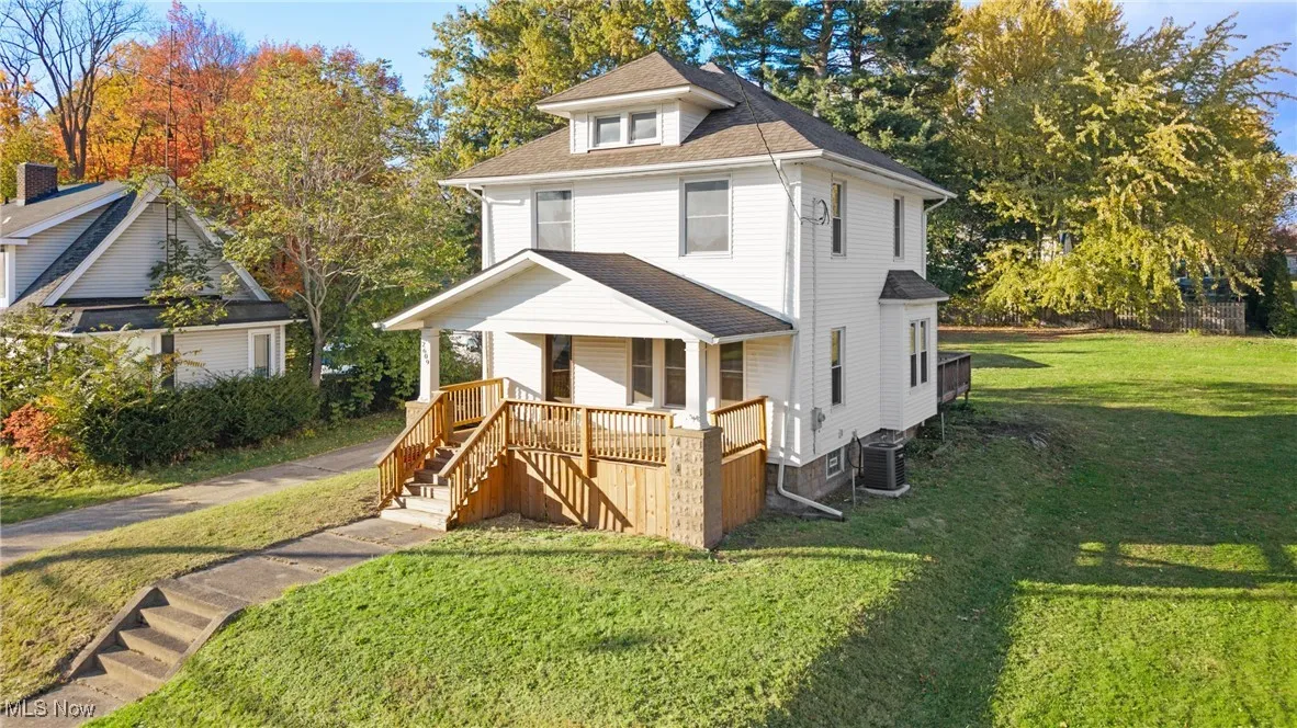 Traditional style home with stairway, a front lawn, roof with shingles, and a porch