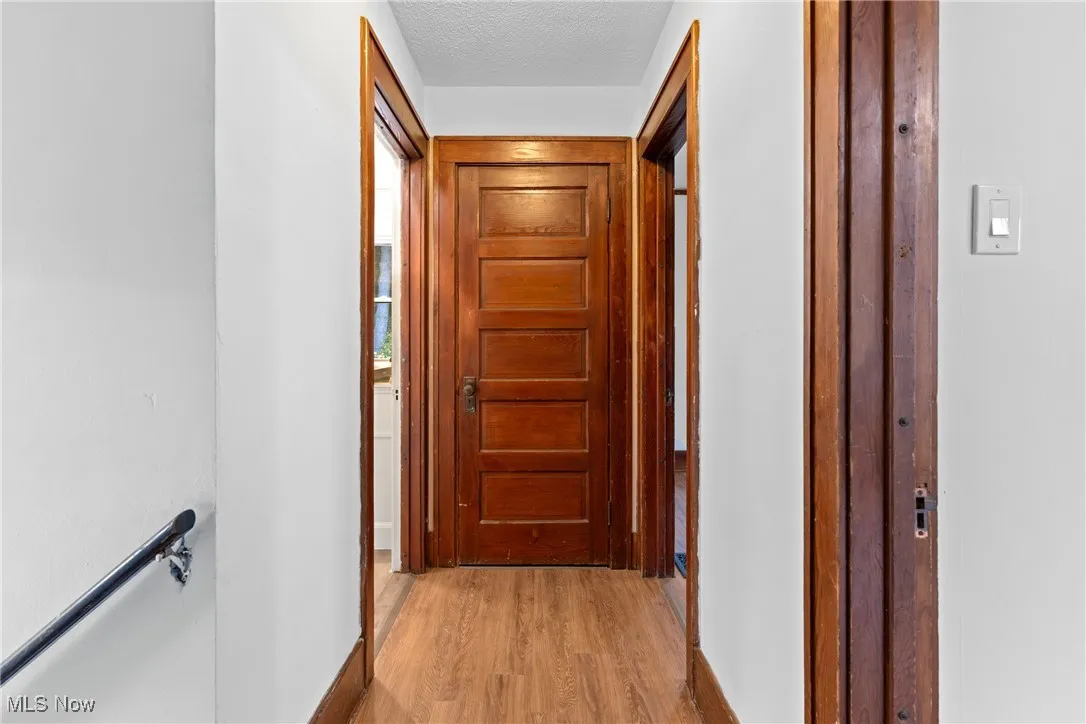 Hall featuring light wood finished floors and a textured ceiling