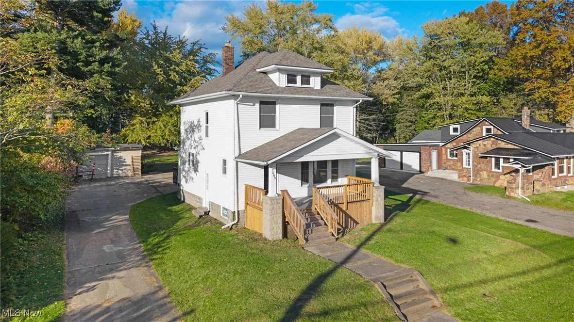 American foursquare style home featuring a chimney, a shingled roof, a front lawn, an outdoor structure, and a detached garage