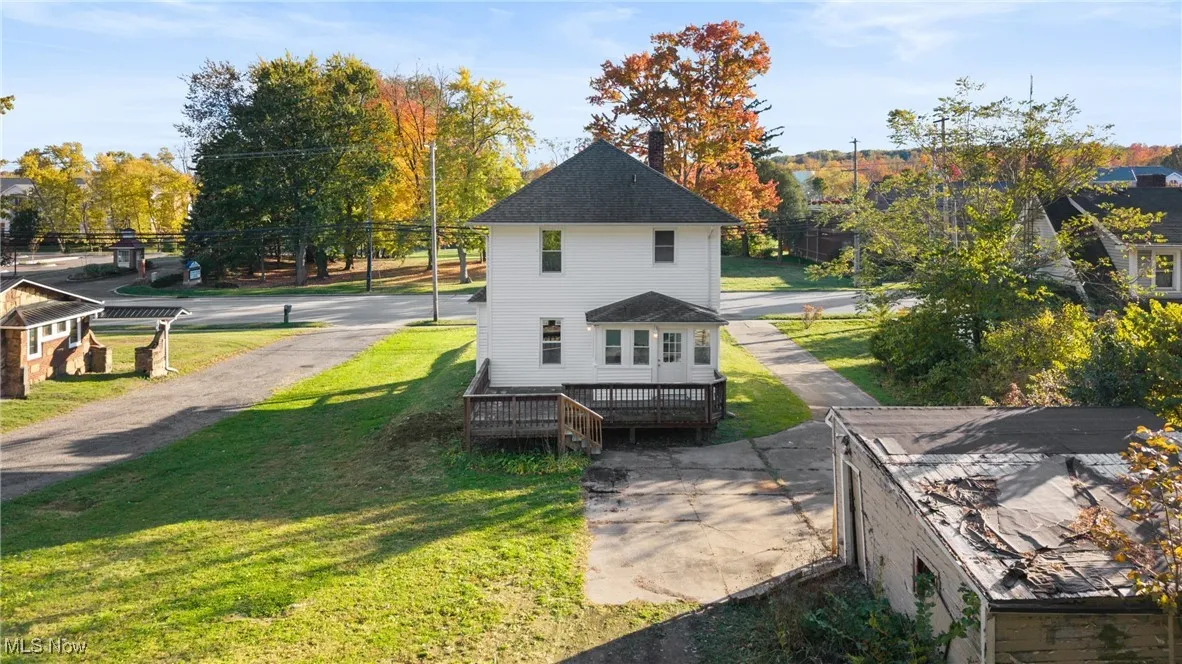 View of side of home with a deck and a lawn