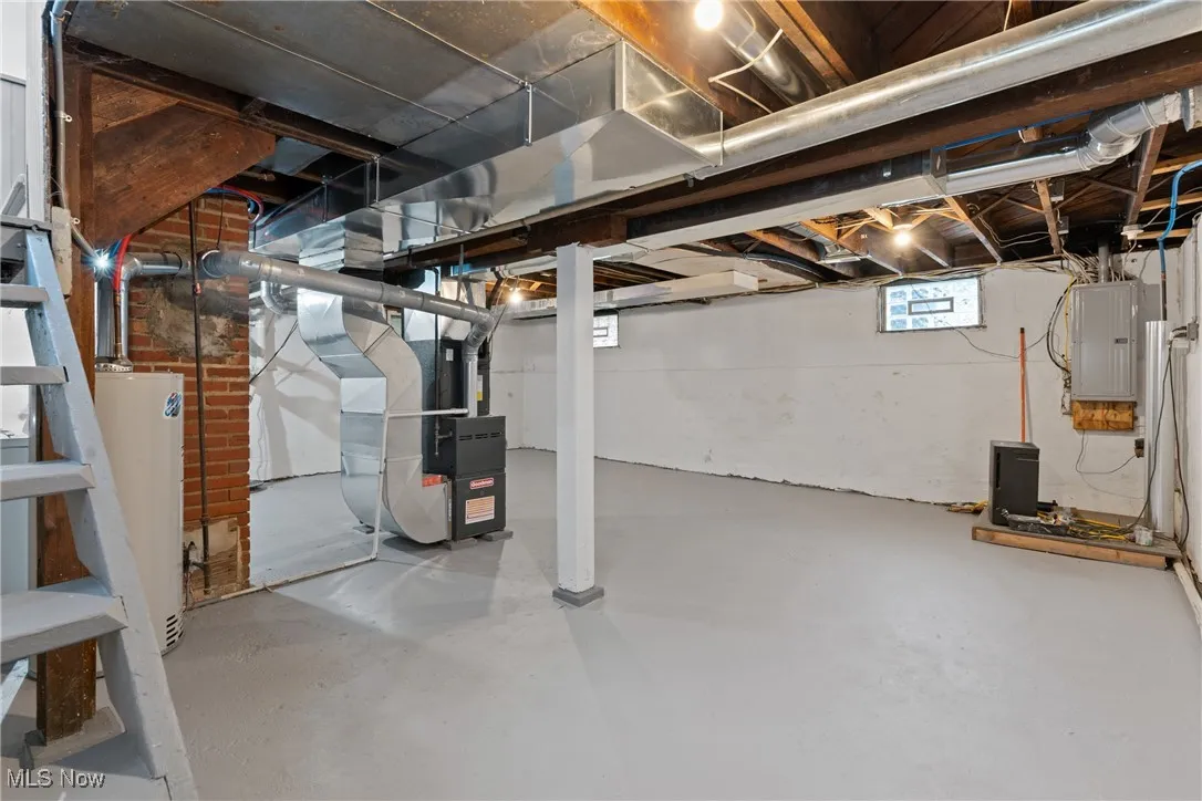 Below grade area featuring electric panel, water heater, and heating unit
