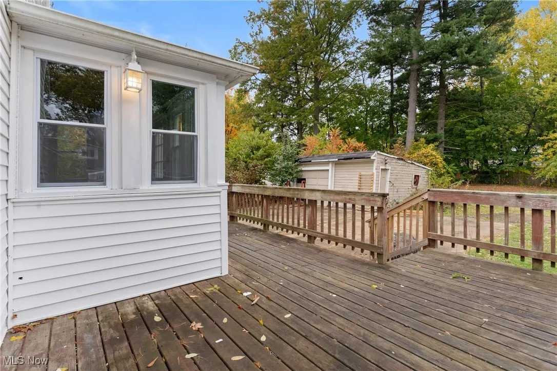 Wooden terrace featuring an outbuilding and view of wooded area