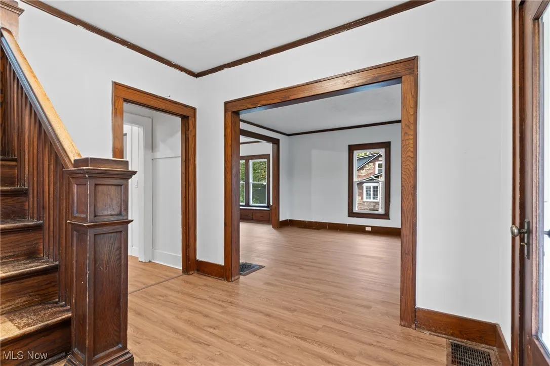 Hall with ornamental molding, stairway, and light wood finished floors