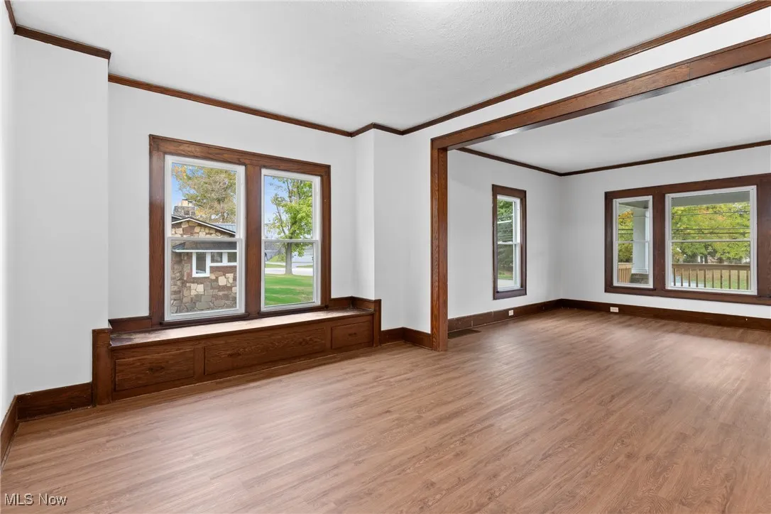 Spare room with wood finished floors and crown molding