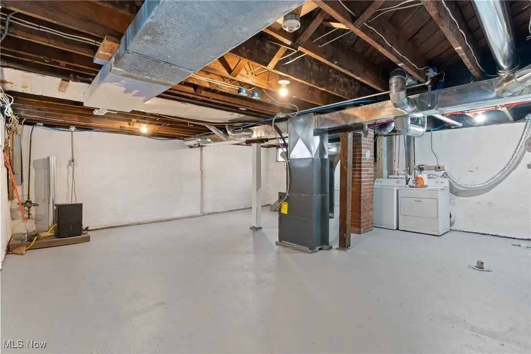 Unfinished basement featuring heating unit and washer and dryer