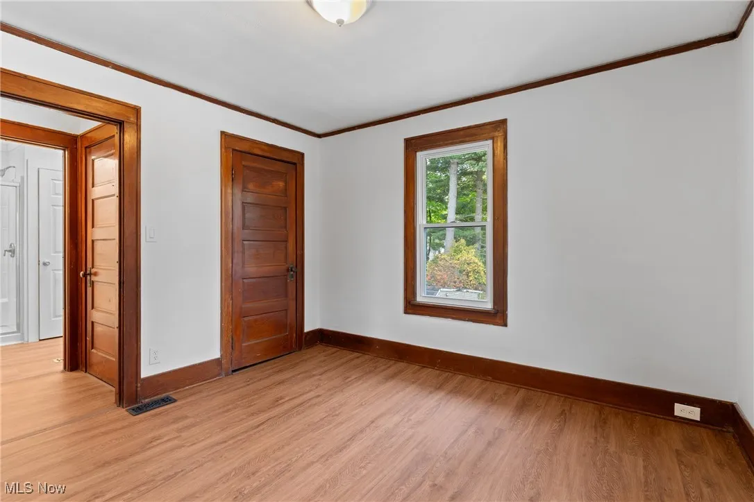 Empty room featuring ornamental molding and wood finished floors