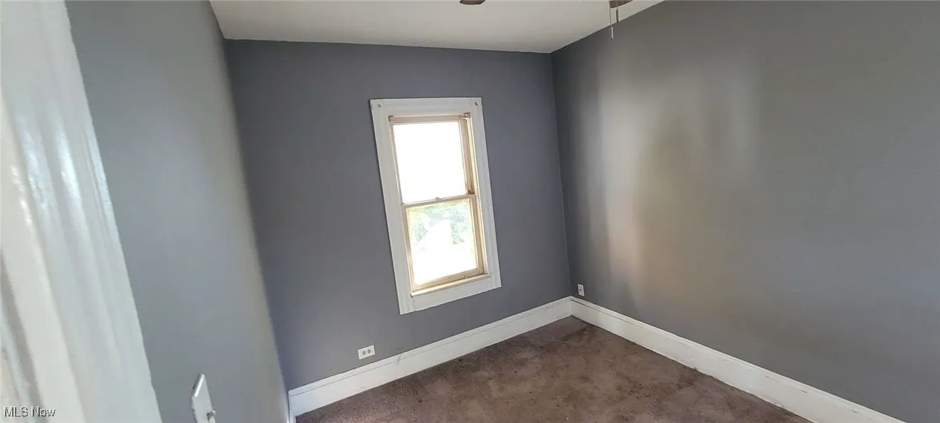Carpeted spare room featuring baseboards and ceiling fan