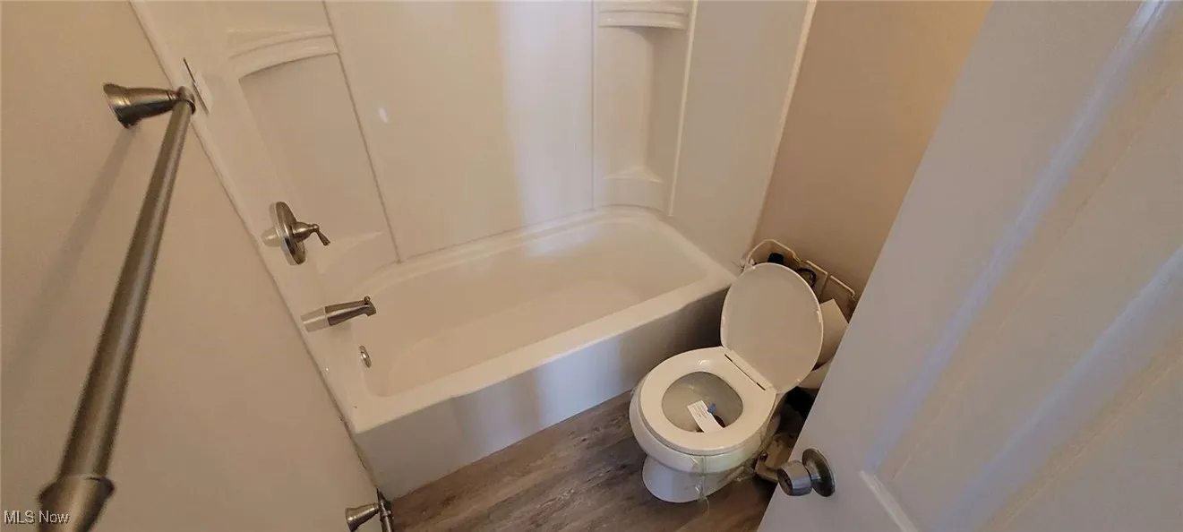 Full bathroom with wood finished floors and shower / washtub combination