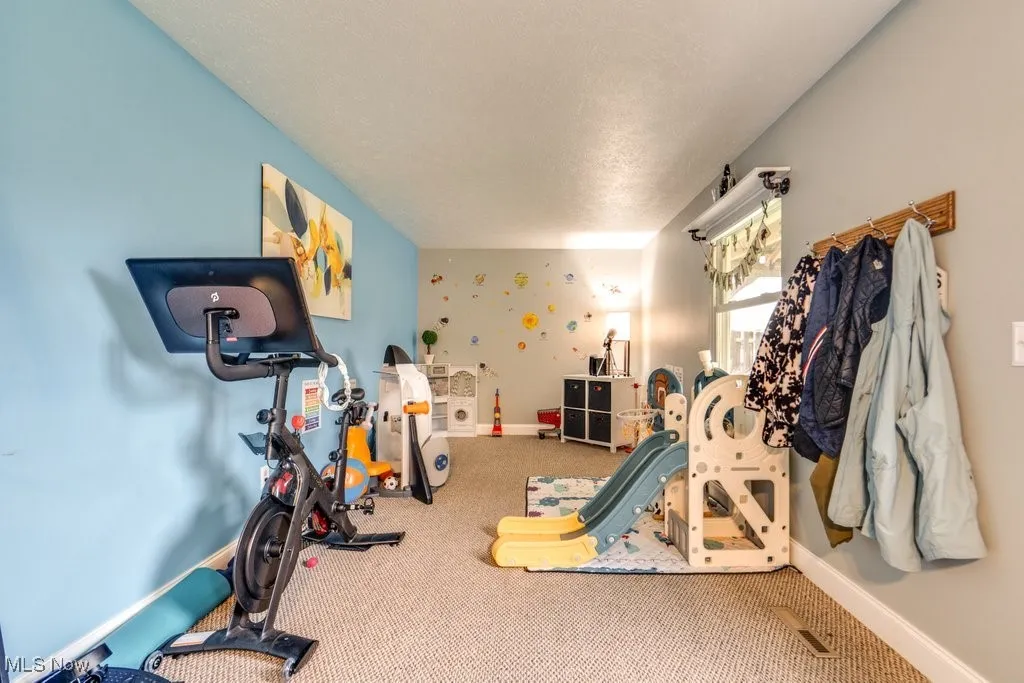 Exercise room with carpet flooring and a textured ceiling