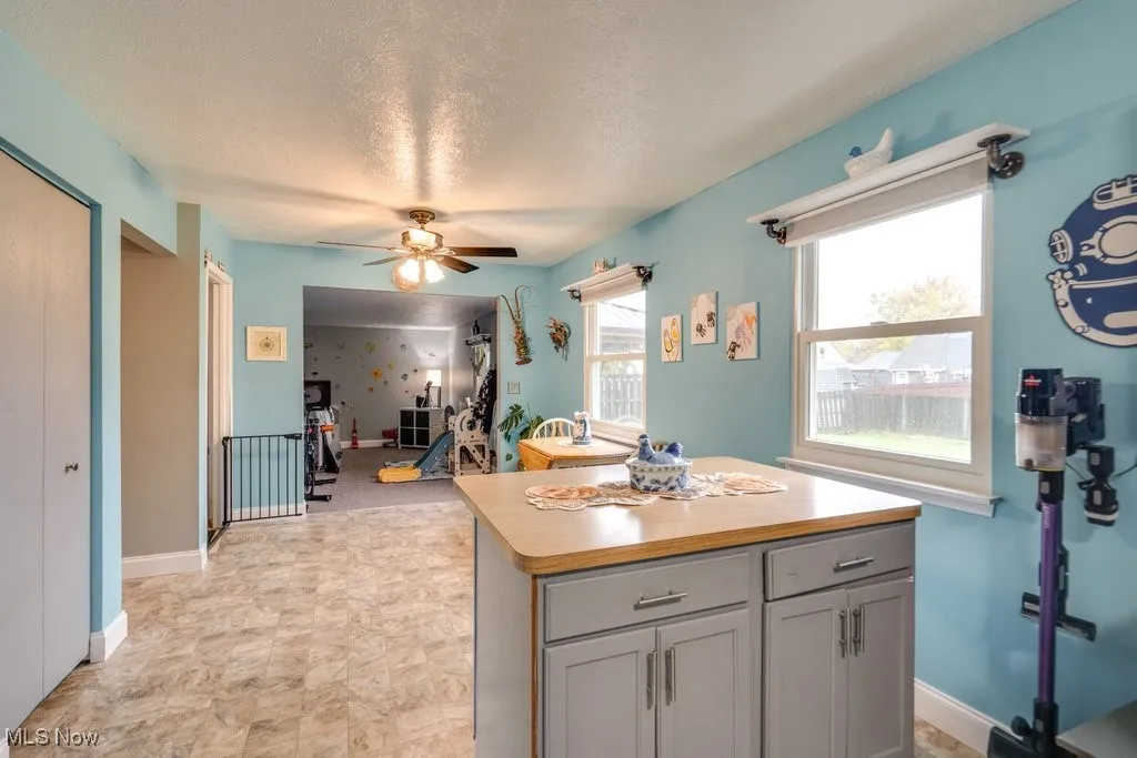 Kitchen with a kitchen island, ceiling fan, a textured ceiling, and gray cabinets