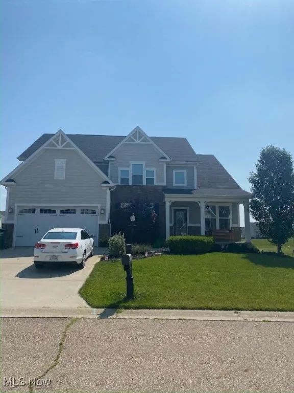 Craftsman-style home featuring a front yard, driveway, and covered porch