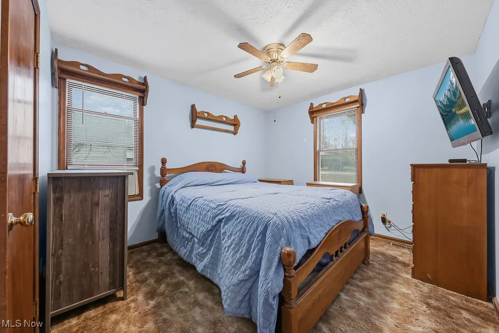 Bedroom featuring dark carpet, a ceiling fan, and a textured ceiling