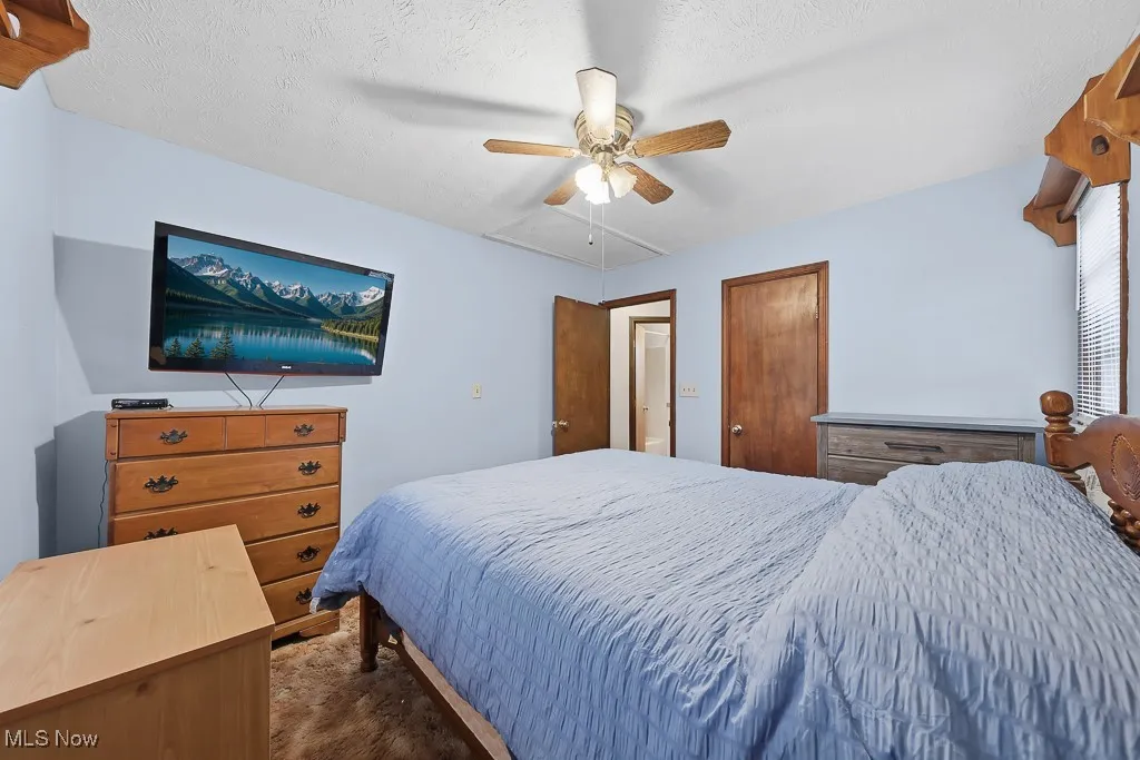 Bedroom with a ceiling fan, a closet, and a textured ceiling