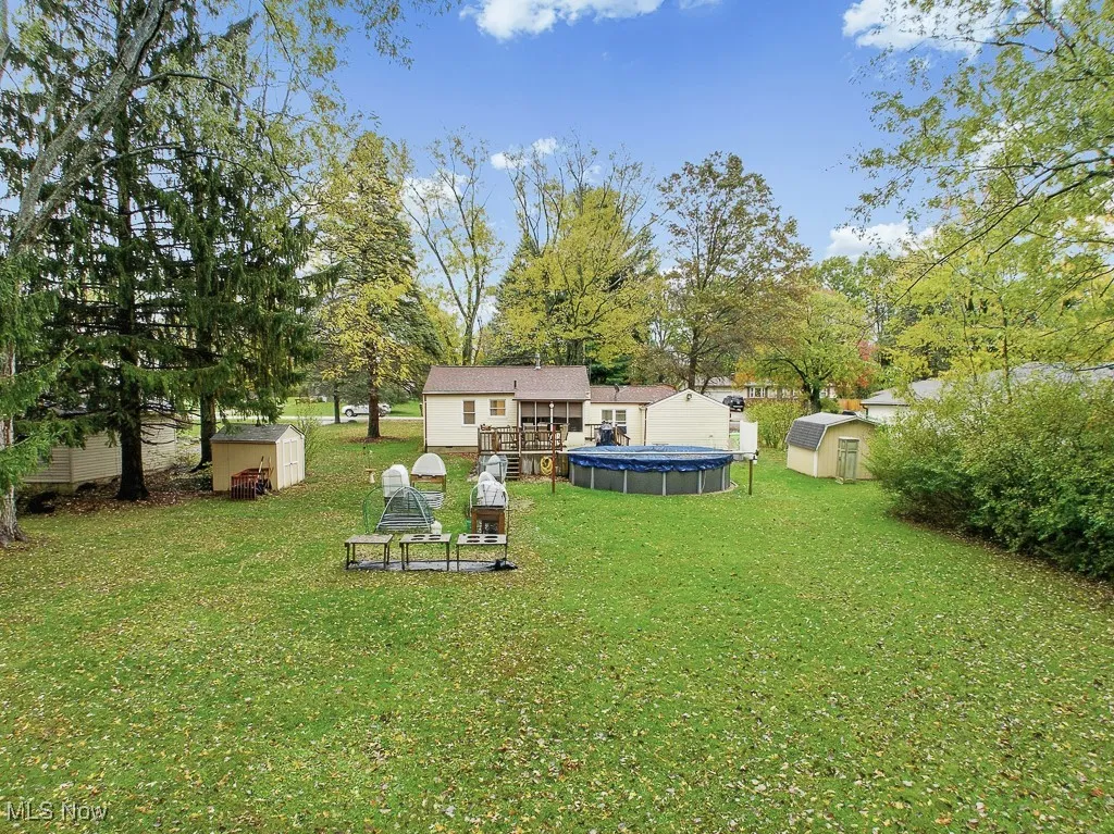 View of green lawn featuring a storage unit and a covered pool