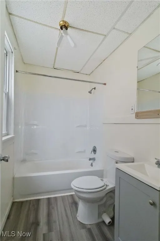 Bathroom featuring wood finished floors, shower / bathtub combination, vanity, and a ceiling fan