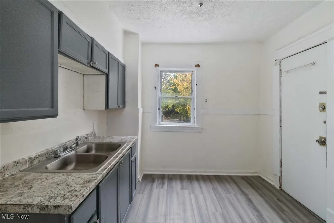 Kitchen with light wood-type flooring, gray cabinets, light countertops, and a textured ceiling