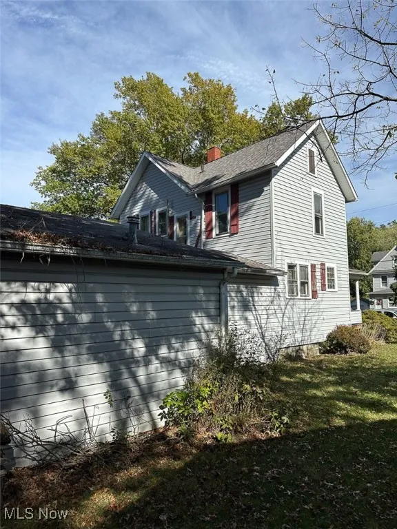 View of home's exterior featuring a chimney and a yard