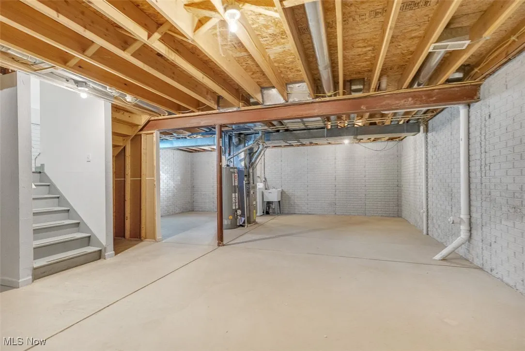 Unfinished basement with stairs and water heater