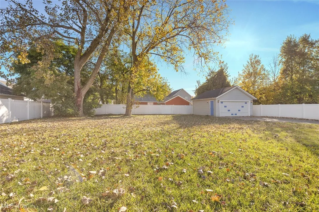 Fenced backyard featuring a detached garage and an outdoor structure