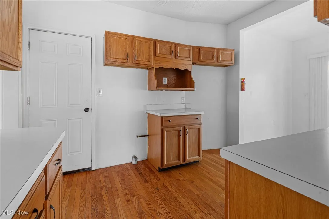 Kitchen with brown cabinetry, light wood-type flooring, and light countertops