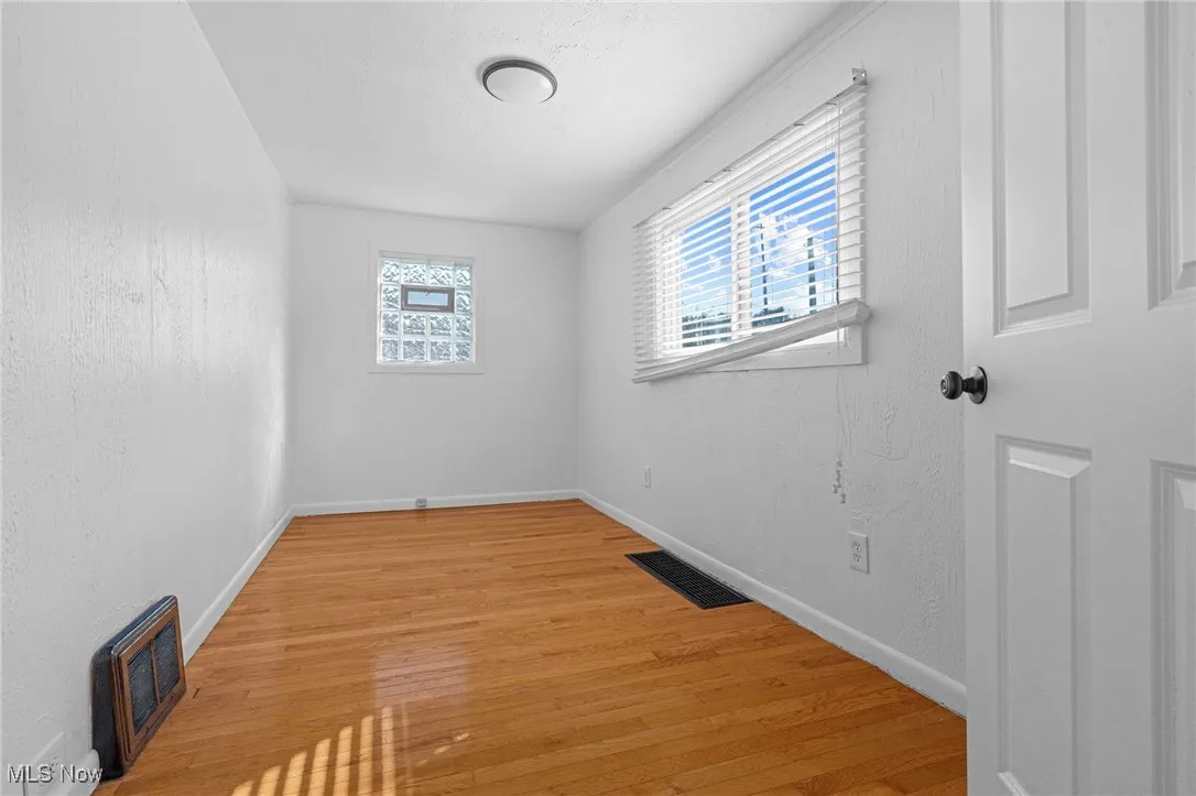 Unfurnished room with a textured wall, plenty of natural light, light wood-style floors, and heating unit