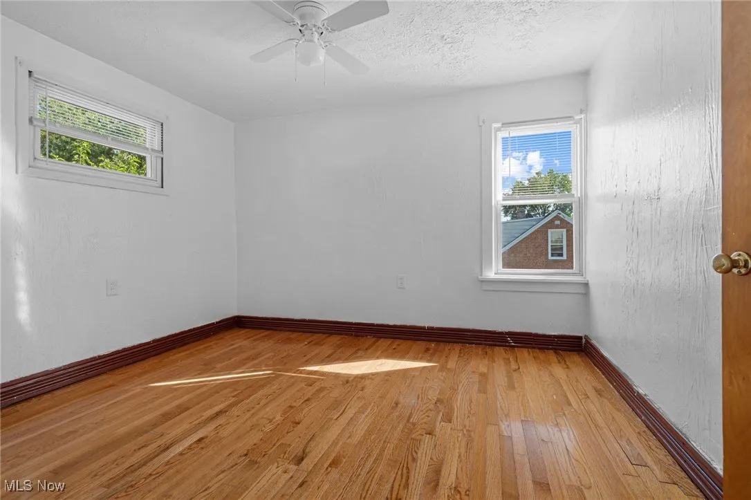 Spare room with light wood finished floors, a textured ceiling, and ceiling fan