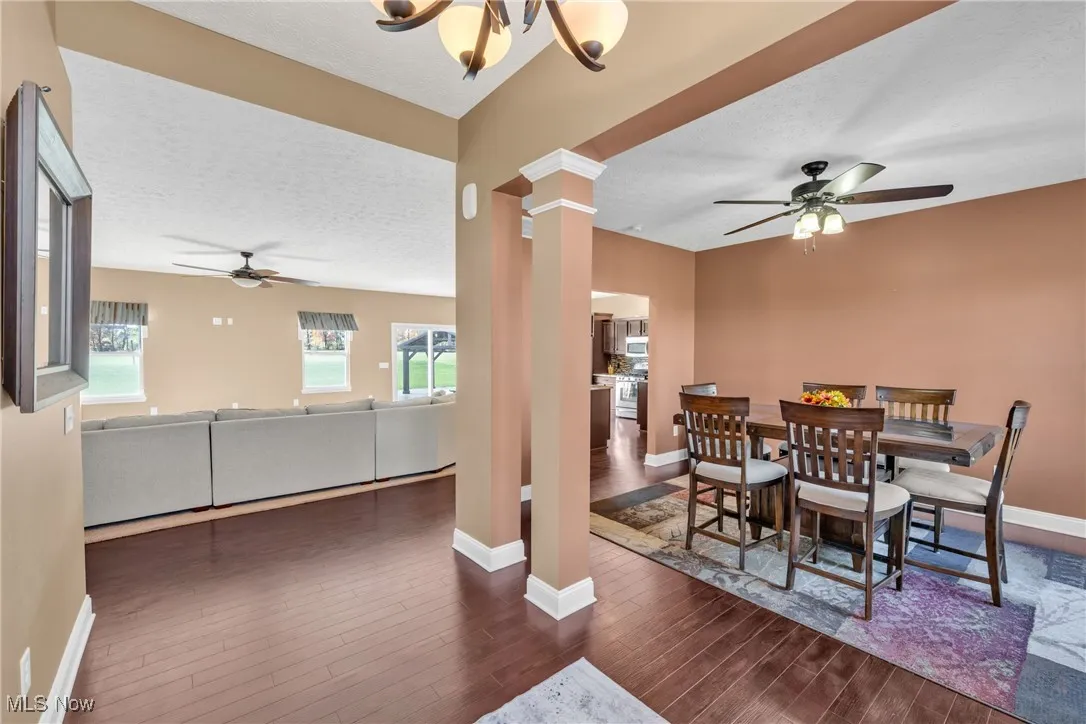Dining space with a ceiling fan, a textured ceiling, dark wood-style flooring, and ornate columns