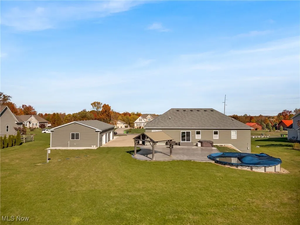 Rear view of house featuring a patio area, a lawn, a residential view, a covered pool, and a gazebo