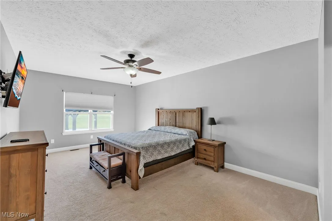 Bedroom featuring light carpet, a textured ceiling, and ceiling fan