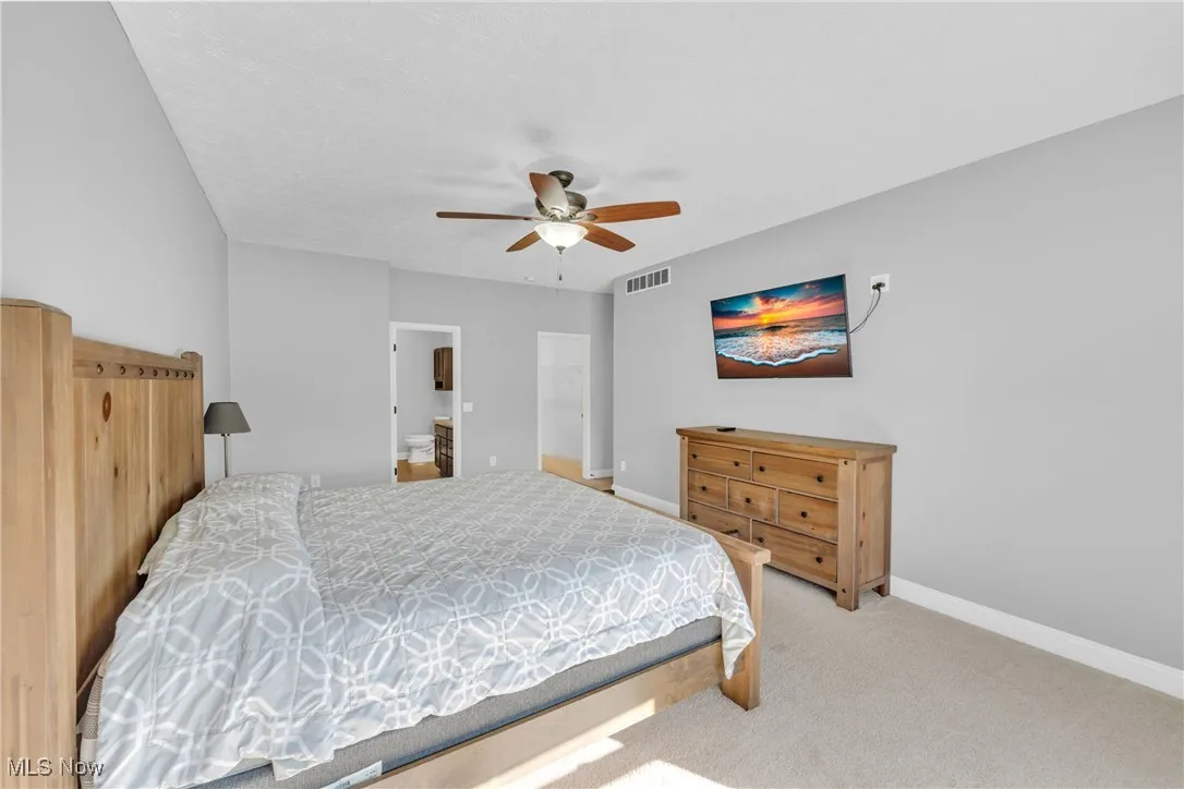 Carpeted bedroom featuring a ceiling fan and connected bathroom