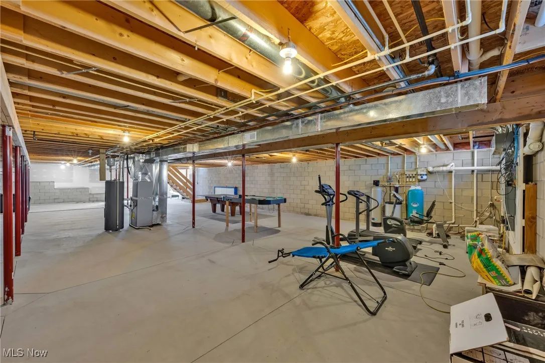 Unfinished below grade area with heating unit, water heater, and a water pressure tank