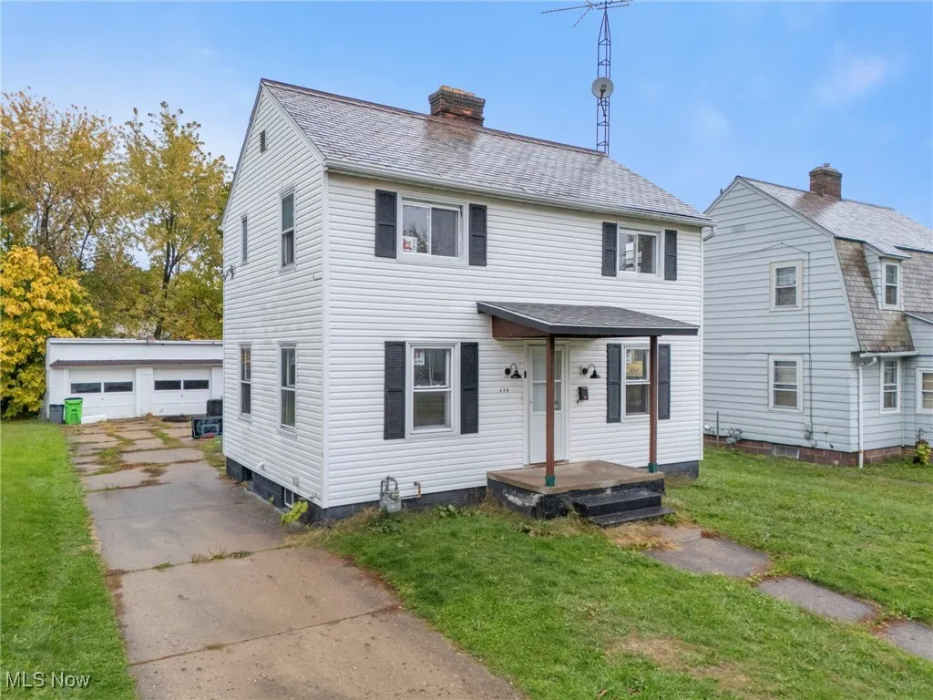 View of front of property with an outdoor structure, a front lawn, a garage, a chimney, and a shingled roof