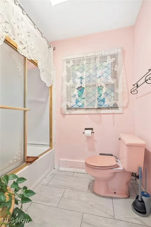 Bathroom with toilet and enclosed tub / shower combo