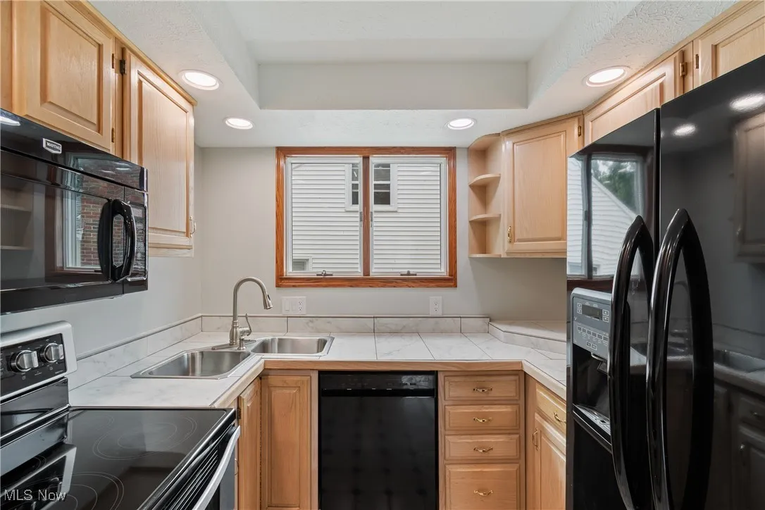 Kitchen featuring black appliances, open shelves, recessed lighting, light brown cabinets, and a raised ceiling